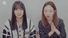 two girls wearing ear buds and a twice logo