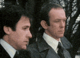 two men are standing next to each other and looking at the camera