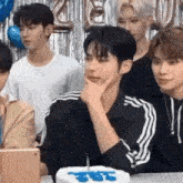 a group of young men are sitting at a table with a birthday cake .