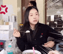 a girl is sitting at a table eating food with a spoon and fork .