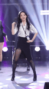 a woman in a white shirt and black skirt is standing on a stage .
