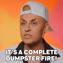 a man wearing a baseball cap and a white shirt says it 's a complete dumpster fire