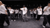 a group of people are dancing in a room and one of their shirts says ' a '