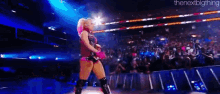 a woman is standing on a stage in front of a crowd of people .