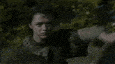 a man in armor is holding a sword while standing next to another man .