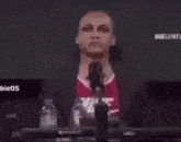 a man is sitting in front of a microphone with his hands up .