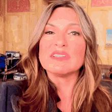 a close up of a woman 's face with a painting in the background that says ' o ' on it
