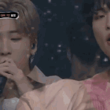 a man singing into a microphone next to another man