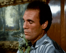 a man in a striped shirt holds a lizard in his hand
