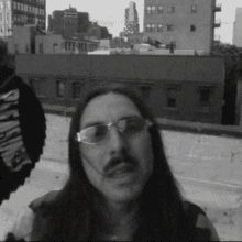 a black and white photo of a man with long hair wearing sunglasses