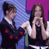 two girls in school uniforms are standing next to each other and making faces .