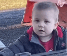 a baby is sitting in a playground with a butterfly on his head .
