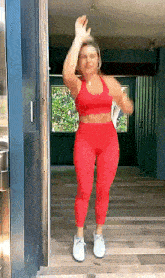 a woman in a red sports bra and leggings is standing in a doorway