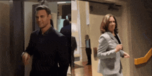 a man in a suit and a woman in a suit are walking in a hallway