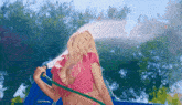 a woman in a bikini is spraying water from a hose .