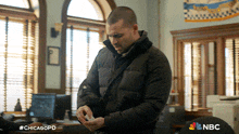 a man in a black jacket is standing in a room with nbc written on the bottom right