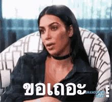 a woman is sitting in a chair with a choker around her neck and a foreign language on her face .