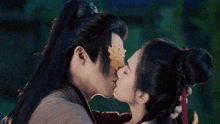 a man and a woman are kissing with a leaf covering their faces .