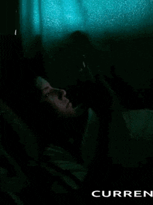 a person is laying in bed looking at a cell phone .
