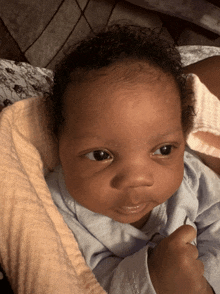 a baby in a blue shirt is laying on a bed