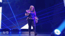 a female wrestler is walking on a stage holding a wrestling belt