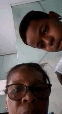 a woman wearing glasses and a boy wearing sunglasses are posing for a picture together .