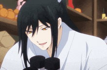 a man with long black hair is looking through a microscope and smiling