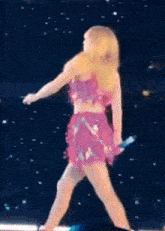 a woman in a pink sequined dress is singing into a microphone .