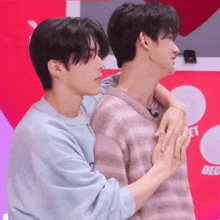 two young men are hugging each other while holding hands .