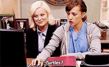 two women are looking at a computer screen with a box that says turtles on it .