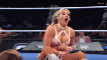 a woman in a wrestling ring with the letter w on the corner