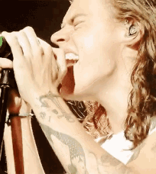 a man singing into a microphone with a tattoo on his arm