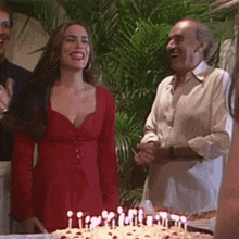 a woman in a red dress stands in front of a birthday cake with candles