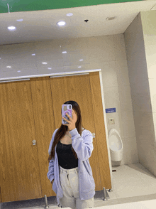 a woman is taking a picture of herself in a public bathroom