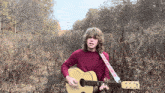 a young man playing a guitar in a field