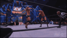 two men in a wrestling ring with a aew logo on the screen