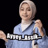 a woman wearing a hijab is smiling and holding a purse with the words ayvey assik written on it