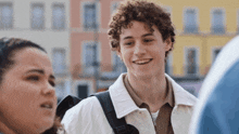 a man with curly hair and a tattoo on his forehead smiles