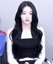 a woman with long black hair wearing a white shirt