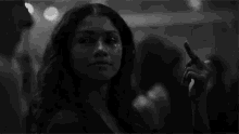 a black and white photo of a woman taking a selfie in a crowd .