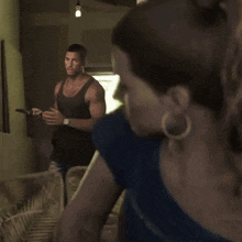 a man in a black tank top looks at a woman in a blue shirt