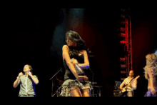 a woman in a black top is singing into a microphone