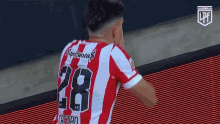 a soccer player wearing a red and white jersey with the number 28 on it