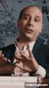 a man in a suit and tie is giving a speech in front of a map of the world