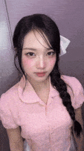 the girl is wearing a pink shirt and a braided hair .