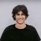 a young man wearing a black t-shirt is looking to the side