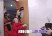a woman in a red dress is standing in a doorway next to a cake