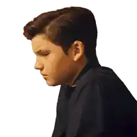 a young boy in a black shirt looks down with a white background