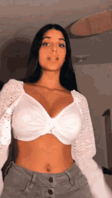 a woman in a white crop top and grey jeans