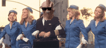 a group of stewardesses are standing around a man in a suit